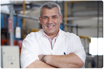 A man with his arms crossed in a factory.